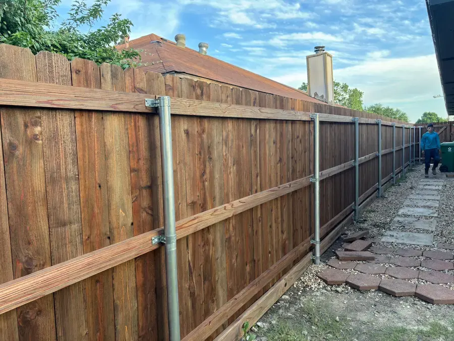Side-by-side cedar privacy fence on galvanized steel posts beside a stepping-stone path